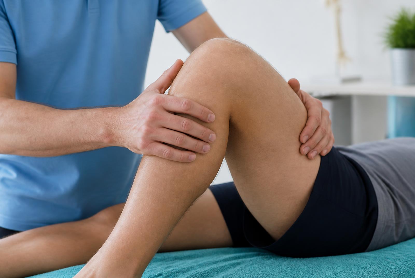 Therapist's hands guiding a patient's knee through a controlled bending movement